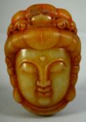 A CHINESE CARVED JADE / HARDSTONE AMULET of a Buhhistic head, the reverse with very fine