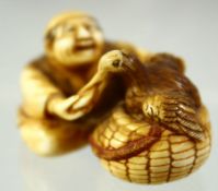 A JAPANESE CARVED IVORY NETSUKE of a seated man hand feeding a bird in a basket, signed to the base,