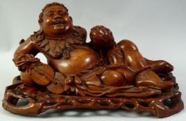 A LARGE CARVED HARDWOOD HOTEI, on a fitted carved hardwood stand, the figure reclining with a
