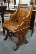 A Gothic revival oak small armchair with pierced sides.