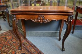 A 19th century rosewood foldover card table of serpentine outline on cabriole legs.