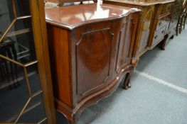 A mahogany serpentine fronted two door cabinet.