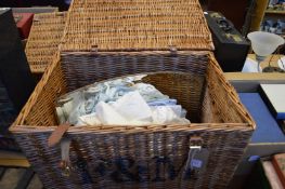 A Fortnum & Mason wicker hamper containing linen and a mirror.