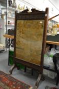 A Victorian oak framed needlework fire screen.