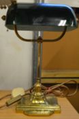 A brass desk lamp with green glass shade.
