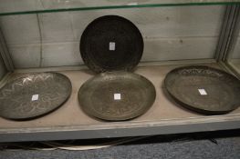 Four Islamic tinned copper dishes with embossed and engraved decoration.