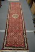 A Persian style red ground runner.