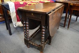 An 18th century oak oval drop-leaf, gate-leg dining table with bobbin turned supports.
