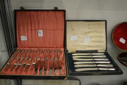 A cased set of six fruit knives and forks and a cased set of six butter knives.