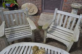 A pair of weathered teak garden armchairs.