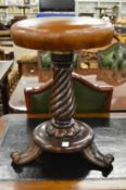 A 19th century mahogany and leather upholstered music seat on wrythen fluted column support with