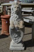 A weathered composite garden ornament modelled as a lion rampant holding a shield.