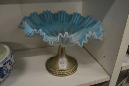 An opaque glass pedestal dish with plated base.