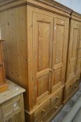 A pine two door wardrobe with drawers below.