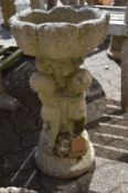 A pedestal birdbath or fountain, modelled with three cherubs.