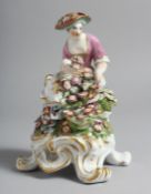 A BOW FIGURE OF SPRING seated on a four footed base while holding flowers.