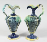 A GOOD PAIR OF FAIENCE POTTERY EWERS with ropework decoration and mermaid handles. 11ins high.