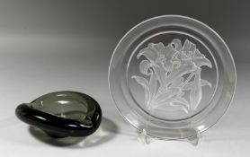 A DANISH SMOKED GLASS ASHTRAY. Signed. 5.5ins and a FLORAL PLATE. Signed. 8ins diameter (2).