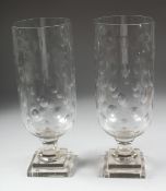 A PAIR OF CUT GLASS HURRICANE LAMPS on square bases. 15ins high