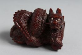 A JAPANESE CARVED WOOD NETSUKE DRAGON. 2ins. Signed.