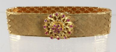 A GOOD WIDE FLEXIBLE GOLD BRACELET with ruby clasp.