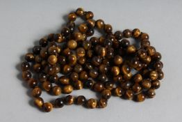 A LONG STRING OF TIGER'S EYE BEADS 46ins long.