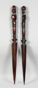 A PAIR OF AFRICAN CARVED WOOD DAGGERS. 24ins long.