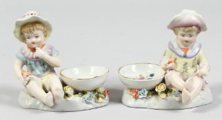 A PAIR OF PORCELAIN SALTS, boy and girl. 4ins high.