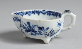 A BOW BUTTER BOAT on three feet painted with flowers and trailing leaves in underglaze blue, the