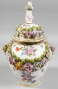 A DRESDEN FLOWER ENCRUSTED VASE AND COVER painted with flowers, with cupid finial. Mark in blue.