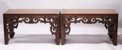 A PAIR OF CHINESE LOW RECTANGULAR TABLES each with a pierced and carved frieze, on square legs.