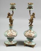 A PAIR OF BRONZE AND CHERUB CANDLESTICKS. 14ins high.