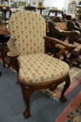 A Queen Anne style oak framed open armchair with needlework upholstered back and seat on shell