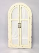 AN UNUSUAL CREAM PAINTED ARCH SHAPED MIRROR with folding doors. 3ft 4ins x 1ft 9ins wide.
