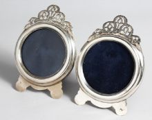 A PAIR OF SILVER CIRCULAR PHOTOGRAPH FRAMES, with pierced cresting on shaped feet. 5ins wide x