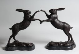 A PAIR OF BOXING HARES, 10ins high, on a marble base.