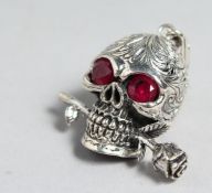 A SILVER AND RUBY EYE SKULL PENDANT.