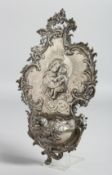 A CONTINENTAL SILVER HOLY WATER STOOP with Madonna and child, scrolls and crystal head. 9ins long