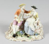 A GOOD FUSTENBERG PORCELAIN GROUP of a young man and girl siting on a bench, a basket of grapes at