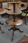 A George III mahogany three tier dumb waiter, the circular supports on a tripod base.