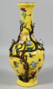 A CHINESE YELLOW GROUND FAMILLE ROSE PORCELAIN VASE decorated in relief with peach blossom, the body