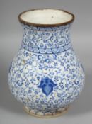 A TURKISH IZNIK BLUE AND WHITE POTTERY VASE, the body painted with swirls of foliate decoration,