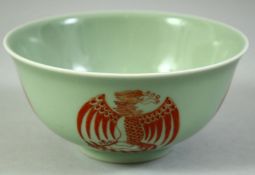 A CHINESE CELADON GLAZED PORCELAIN BOWL, painted in copper red with phoenix, the base with siz