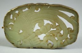 A CHINESE CARVED AND PIERCED JADE AMULET, depicting a bird, the amulet encased in a white metal