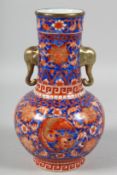A CHINESE BLUE GROUND AND CORAL RED TWIN-HANDLED VASE painted with birds and large flower heads, the