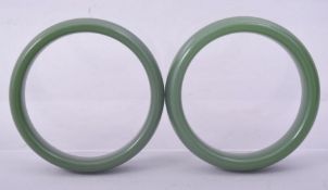 A PAIR OF CHINESE GREEN GLASS BANGLES, 8.5cm.