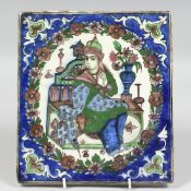 A PERSIAN GLAZED POTTERY TILE, central depicting a seated figure within a floral border, 24cm x 21.