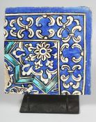 A PERSIAN GLAZED POTTERY CORNER-SECTION TILE painted blue and white foliate pattern and elevated
