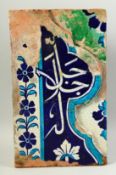 A LARGE ISLAMIC GLAZED POTTERY TILE PANEL with Qur'anic character to the centre. 38cm x 23cm