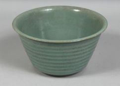 A LARGE CHINESE RIBBED CELADON BOWL, the base with carved characters, 19.5cm diameter.